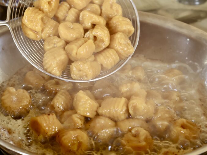 adding cooked pumpkin gnocchi to sauce