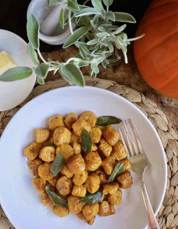 overhead plate of pumpkin gnocchi with sage and a pumpkin