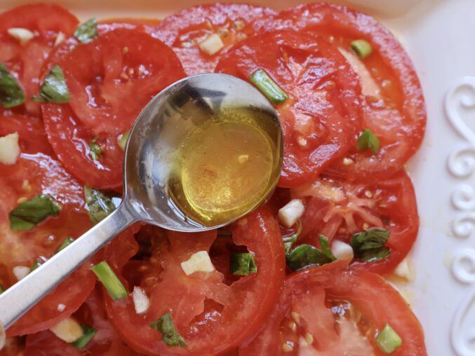 spooning oil over tomatoes