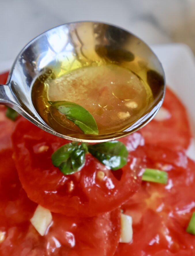 spooning oil over tomatoes