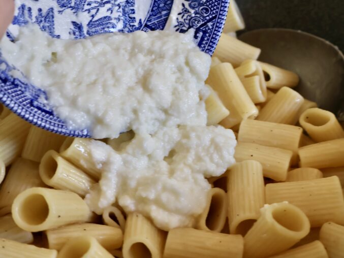 adding cheese to the rigatoni for gricia